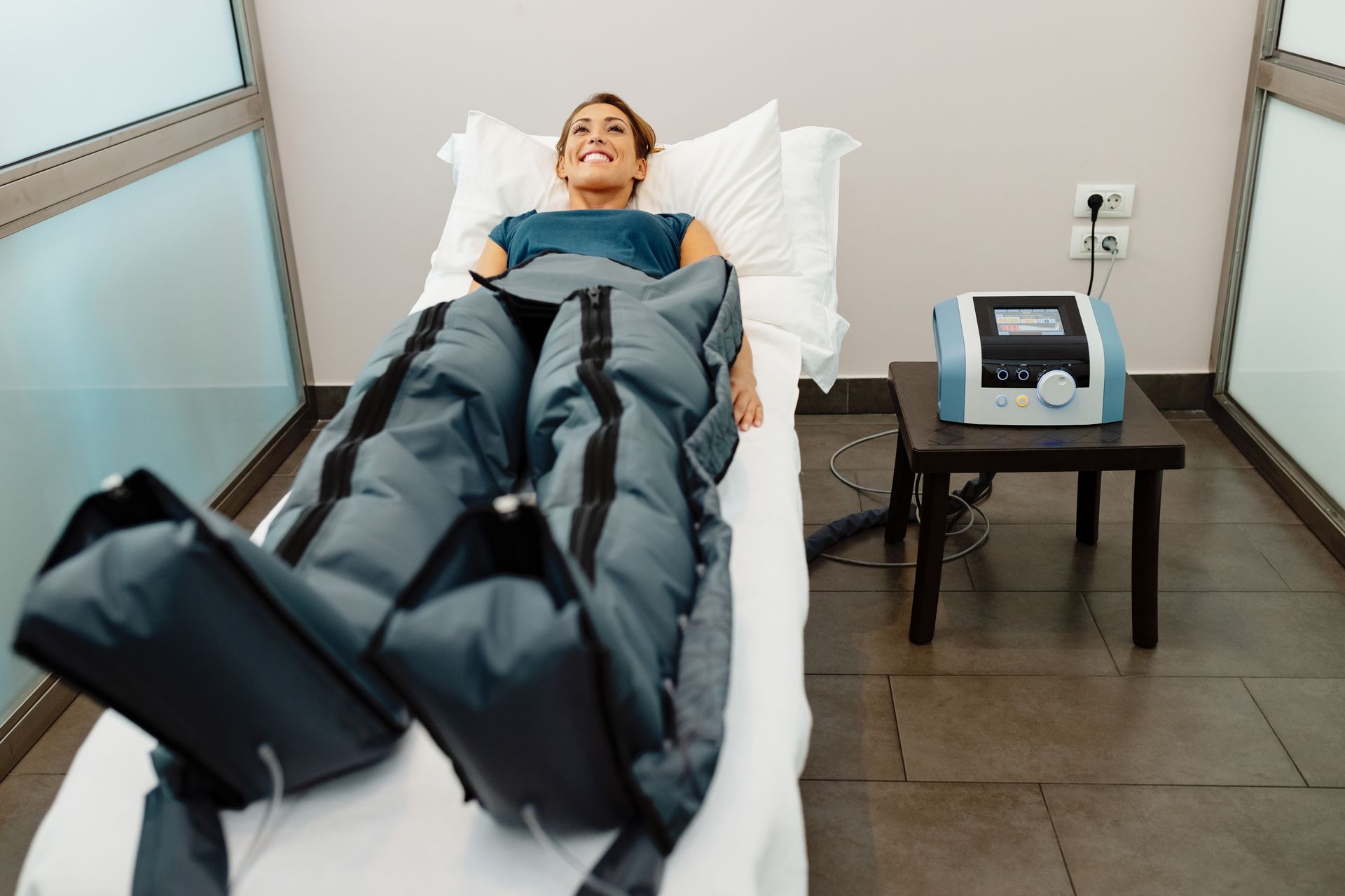 Person lying on a treatment bed wearing compression boots in a clinic room Person lying on a treatment bed wearing compression boots in a clinic room