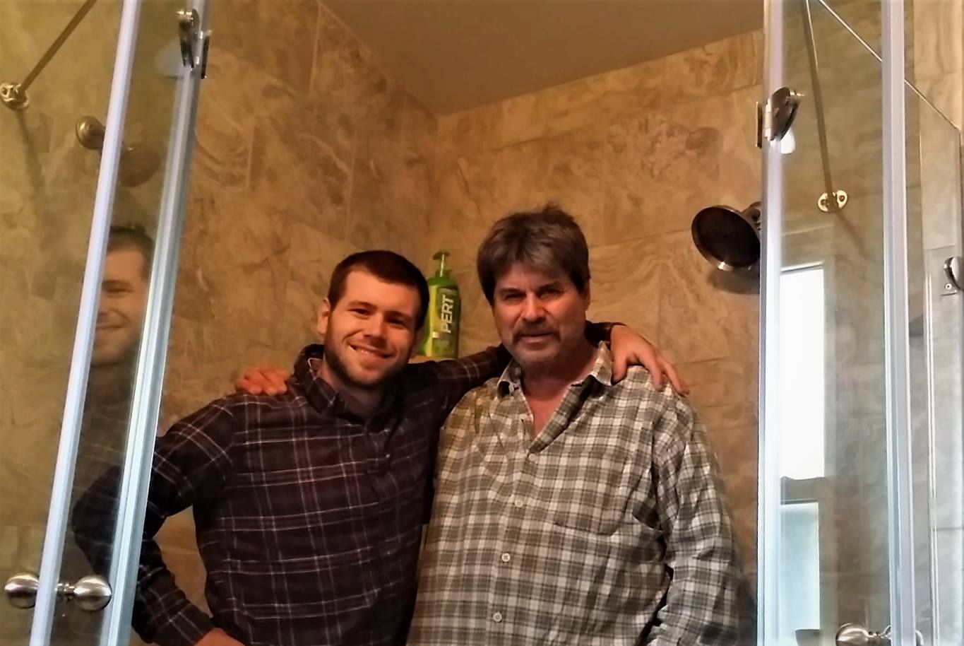 Two men are posing for a picture in a bathroom