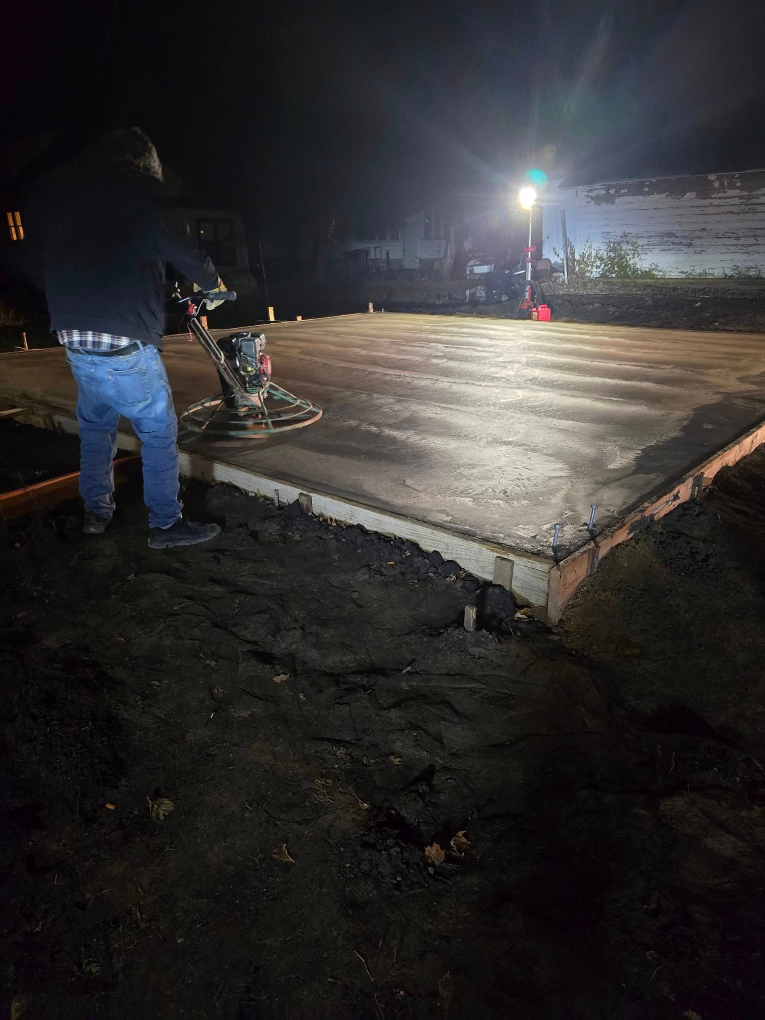 A man is working on a concrete floor at night.