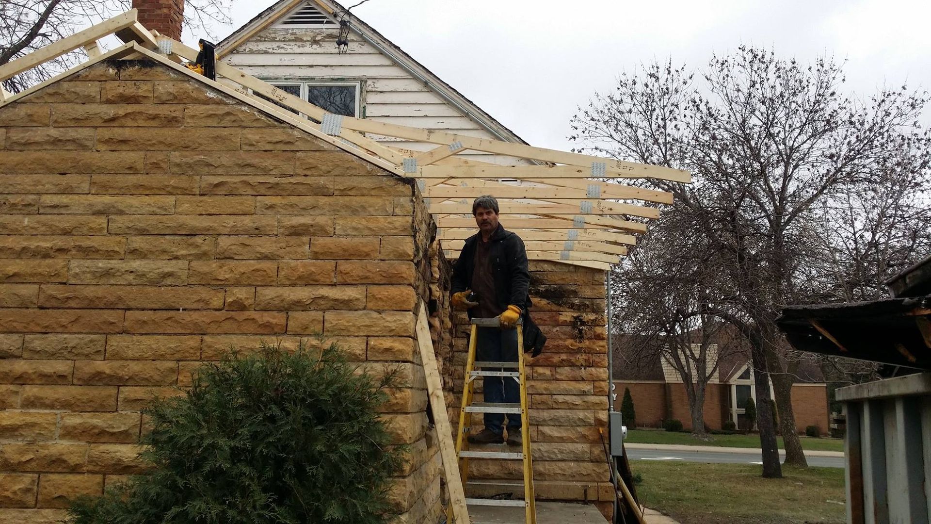 A man is standing on a ladder in front of a house.