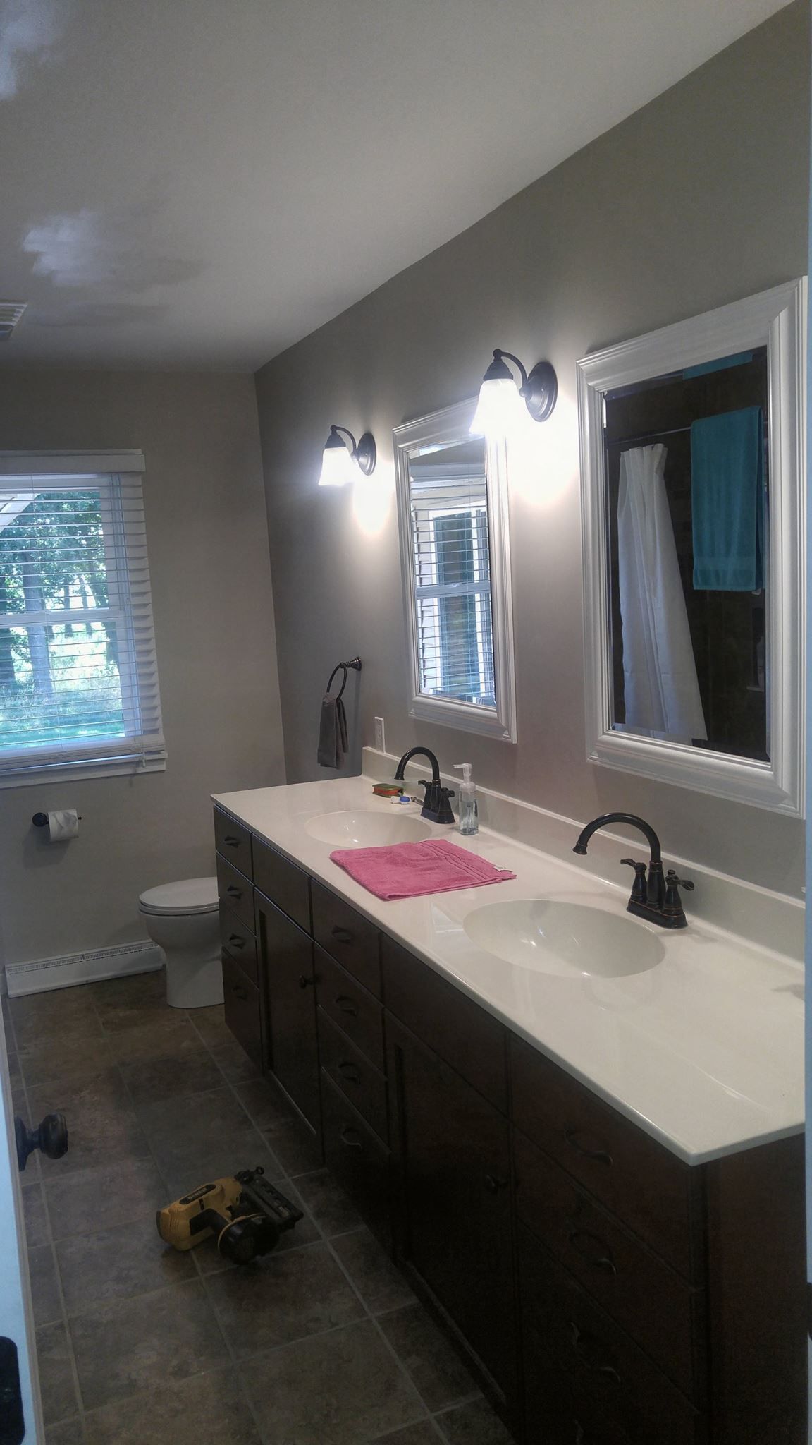A bathroom with two sinks , two mirrors and a toilet.
