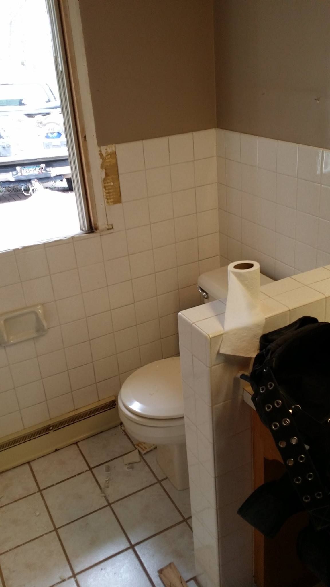 A bathroom with a toilet , sink , and window.
