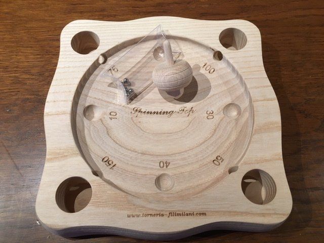 Tavola di legno circolare per puzzle con fessure numerate e quattro grandi fori angolari su un tavolo