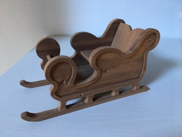 Sagoma decorativa in legno a forma di slitta su una superficie azzurra