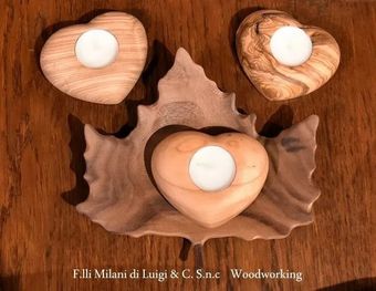 Tre portacandele in legno a forma di foglia con candele bianche su una superficie in legno