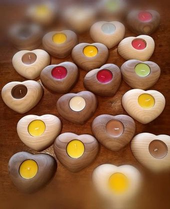 Portacandele in legno a forma di cuore con piccole candele colorate su un tavolo accogliente.