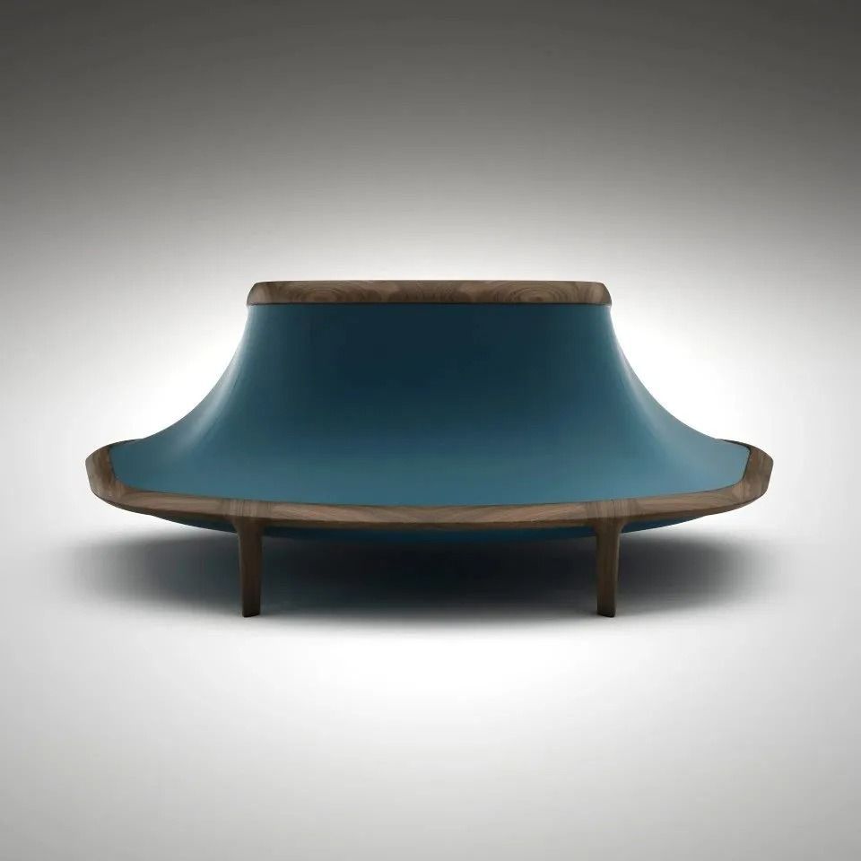 Divano moderno blu con struttura in legno e gambe affusolate su sfondo grigio.