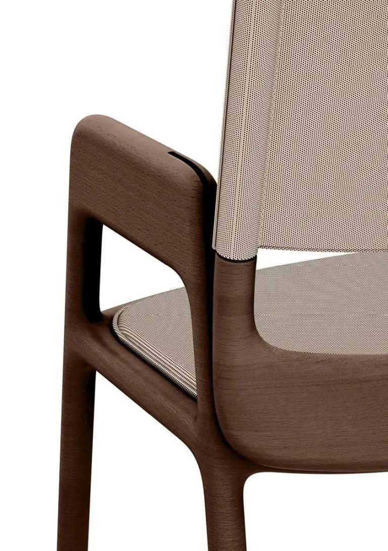 Primo piano di una sedia in legno marrone con rivestimento in tessuto beige intrecciato e dettagli sui braccioli.