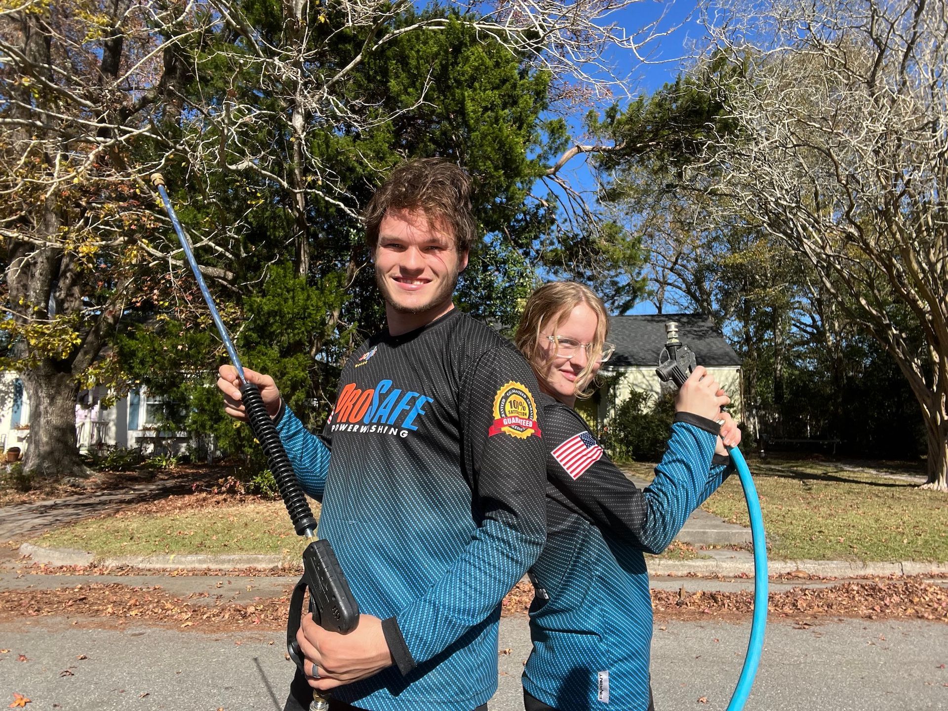 A man and a woman are standing next to each other holding a hose.