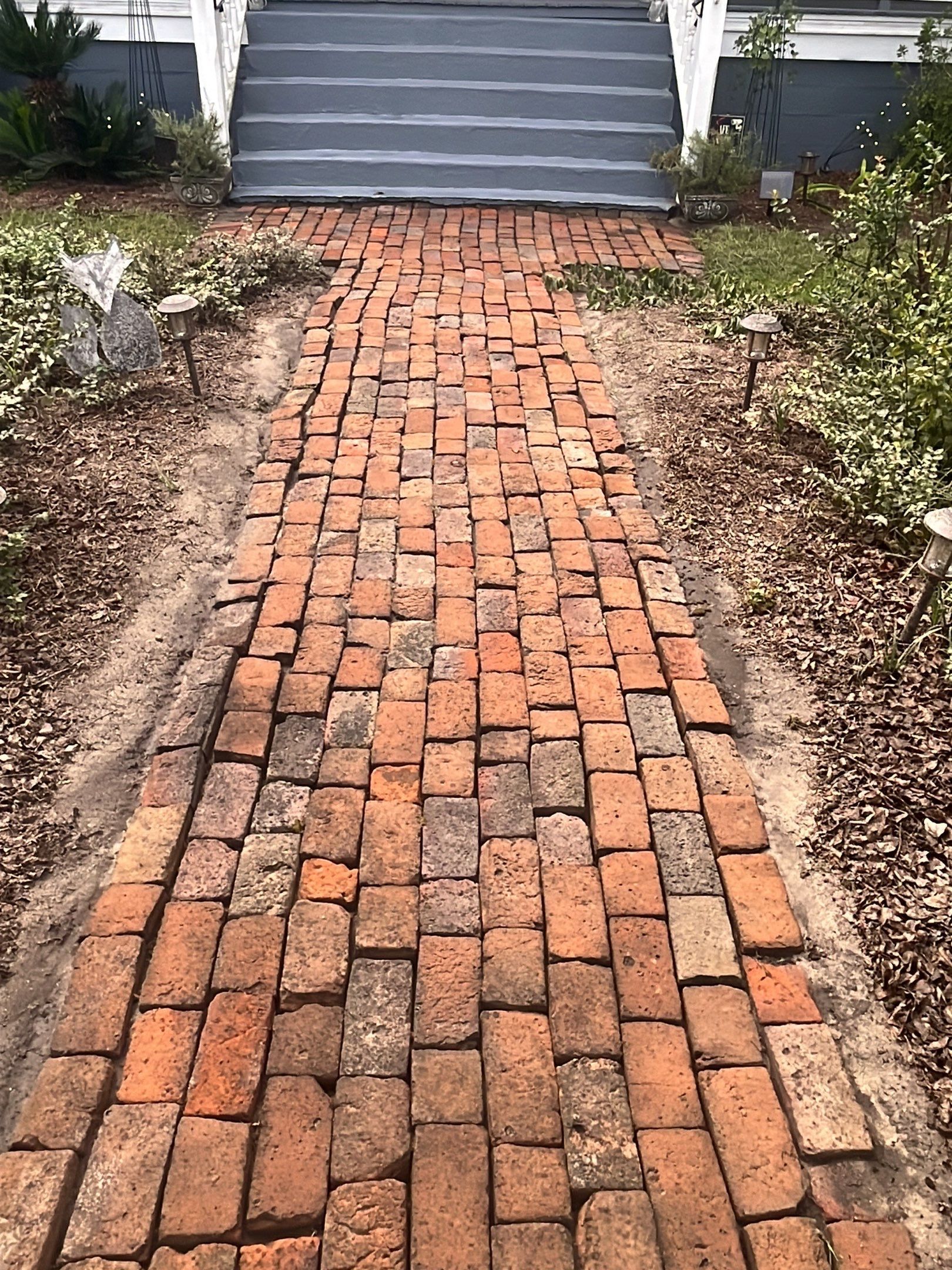 a brick walkway leading to a house with stairs