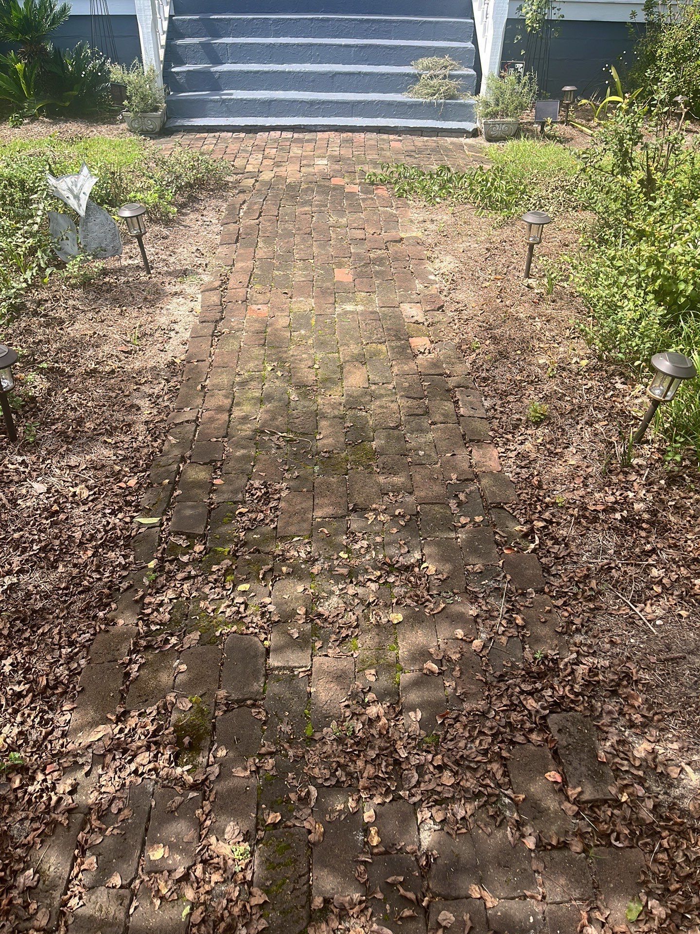 a brick walkway leading to a house with stairs