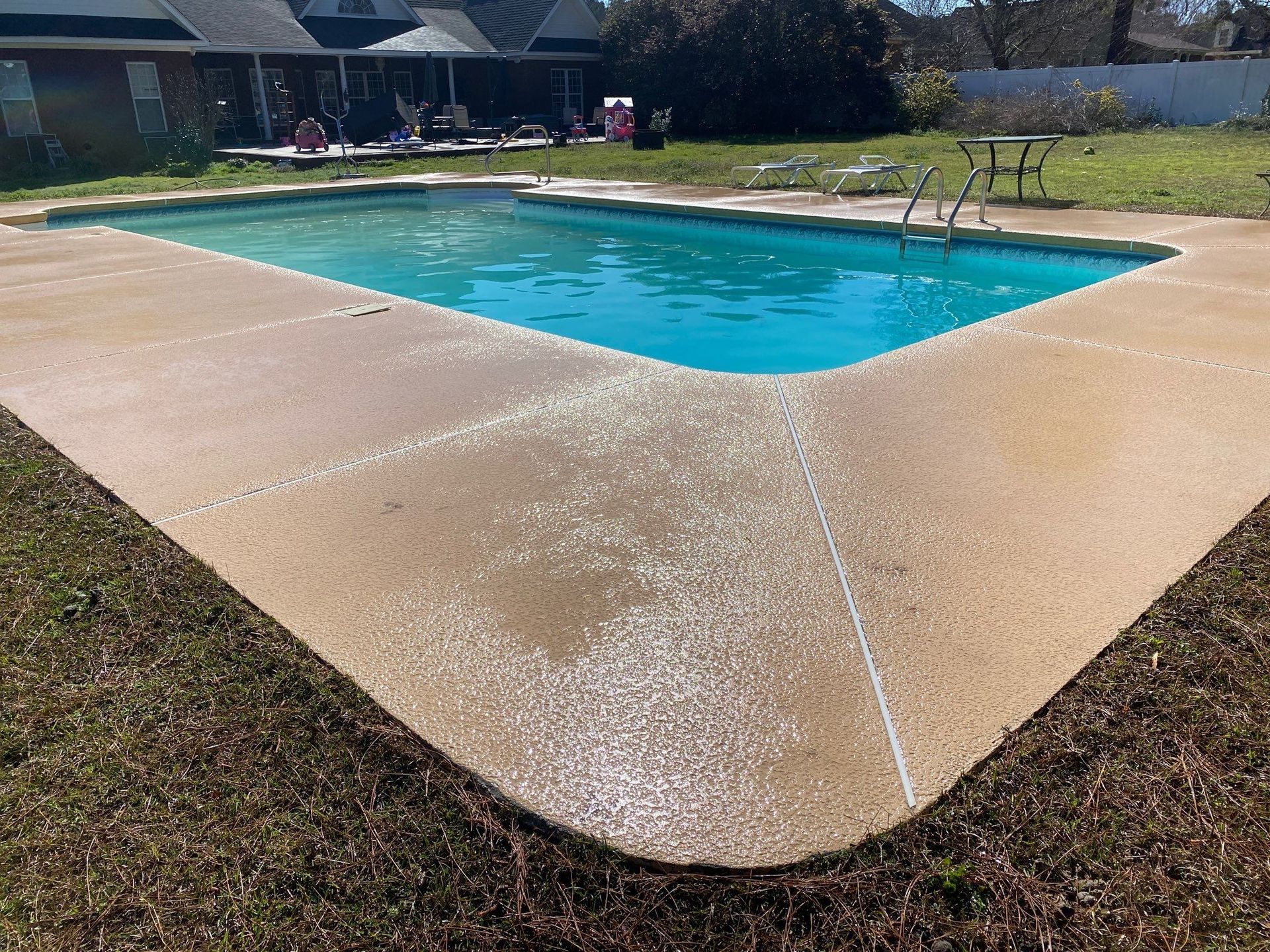 A large swimming pool is sitting on top of a concrete patio.