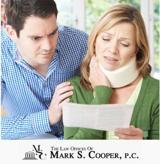 A woman with a neck brace, distressed, reviews paperwork with a concerned man, possibly at home.