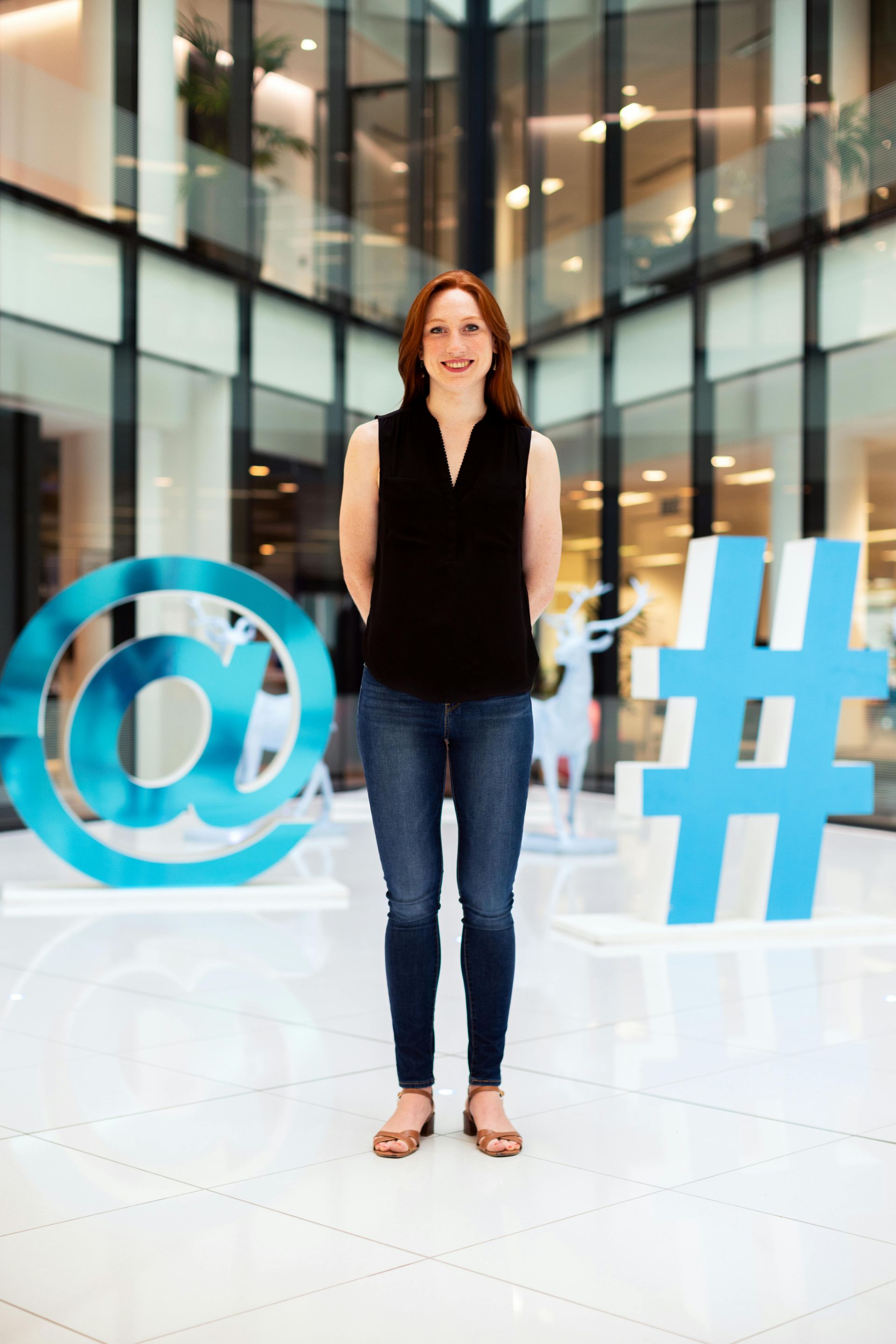 A woman is standing in front of a large hashtag sign.