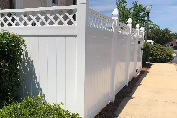 A white fence along a sidewalk next to a house.