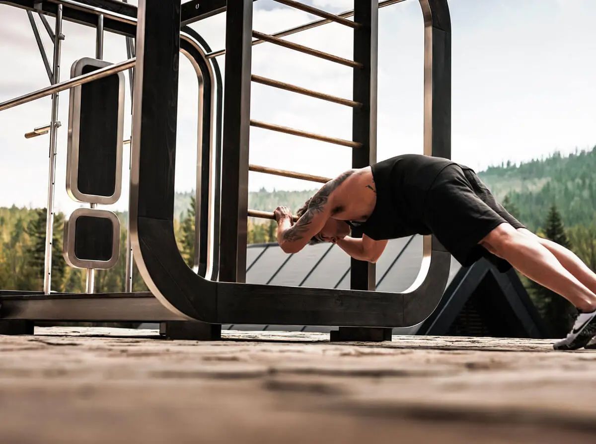 Un homme fait des exercices du dos sur une structure de gym extérieure avec une vue panoramique.