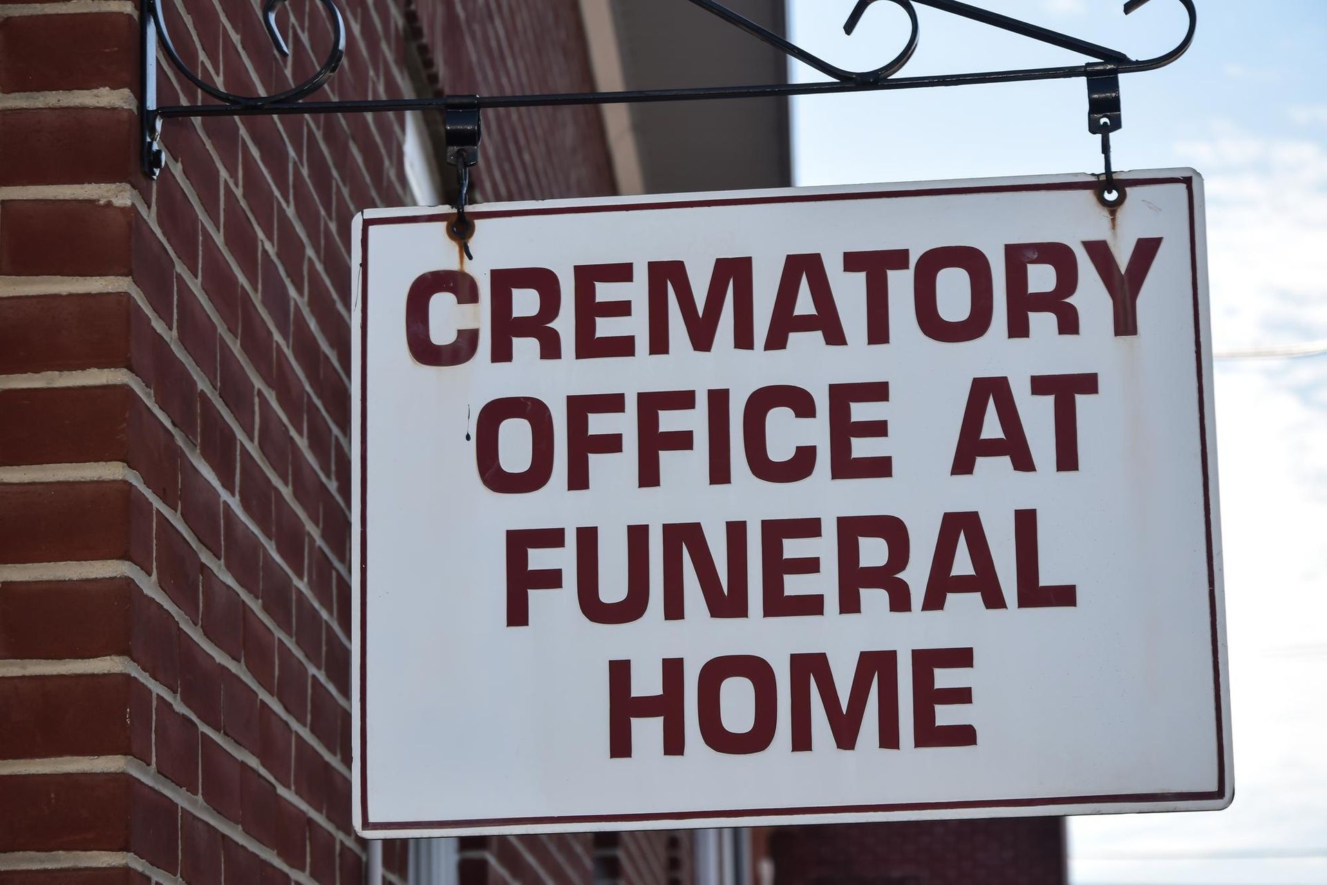 Sign reading “CREMATORY OFFICE AT FUNERAL HOME” on a brick building