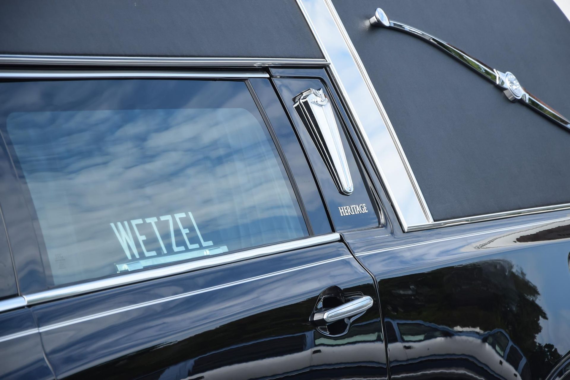 Black classic car with tinted window and chrome trim, showing the name “WETZEL” on the glass