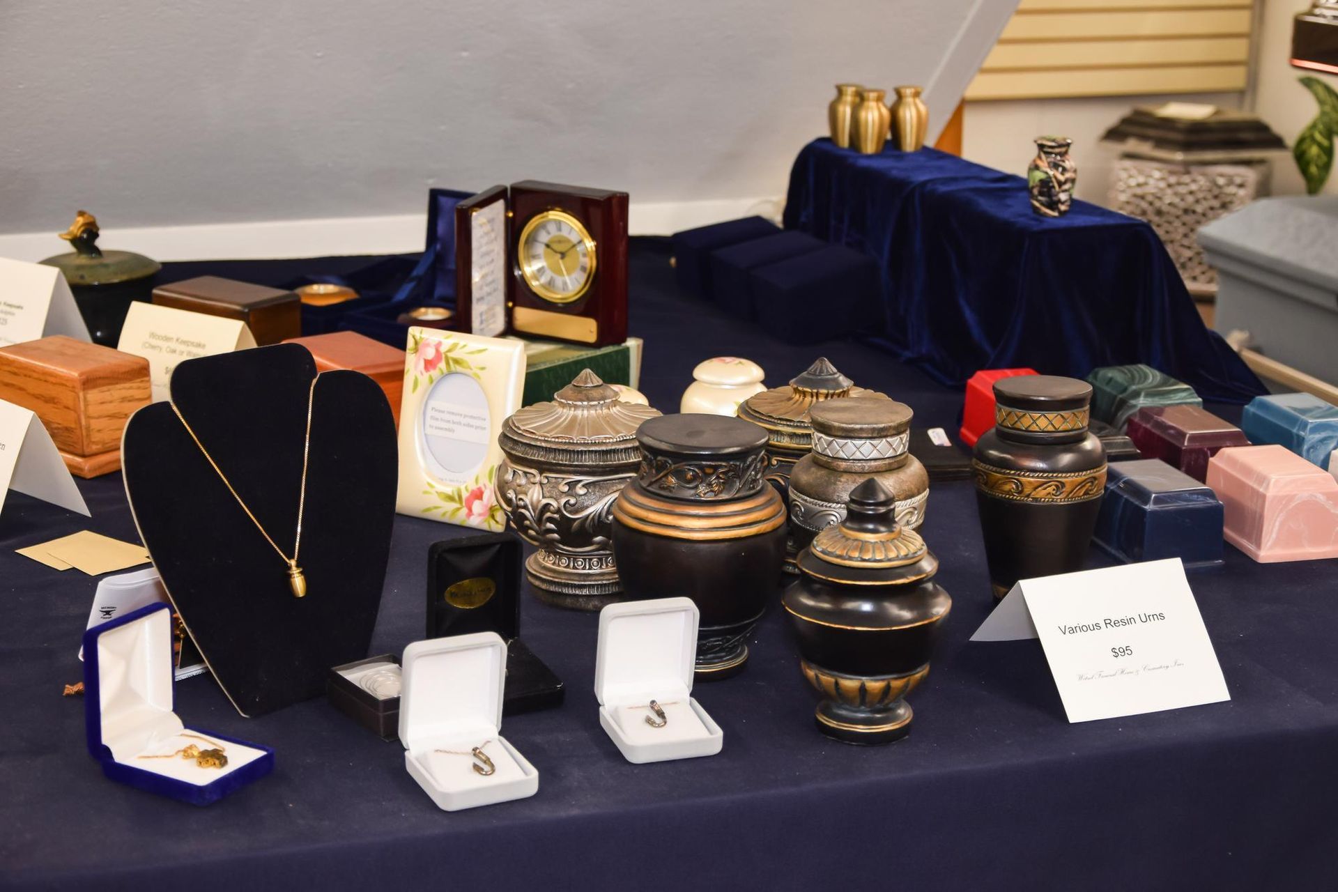 Display of jewelry, watches, and decorative boxes on a table covered in dark cloth