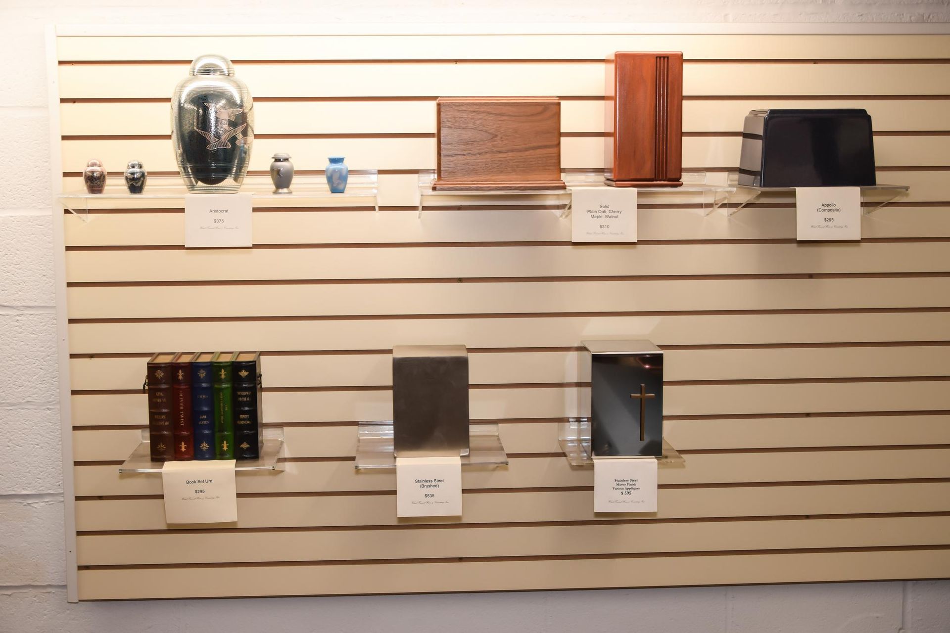 Wall display of assorted products on slatboard shelves, including a mask, wood panel, black case, and small items