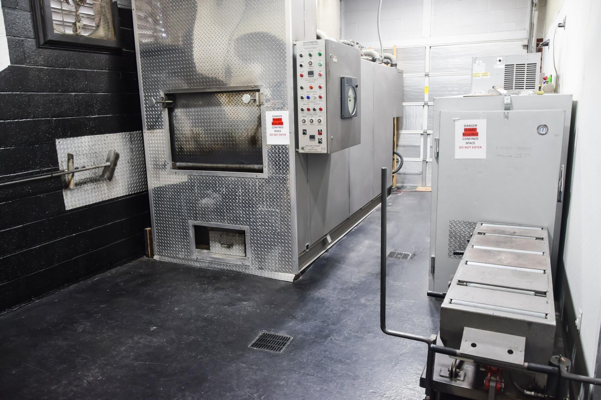 Industrial room with large silver HVAC or refrigeration units and control panels on black walls and floor