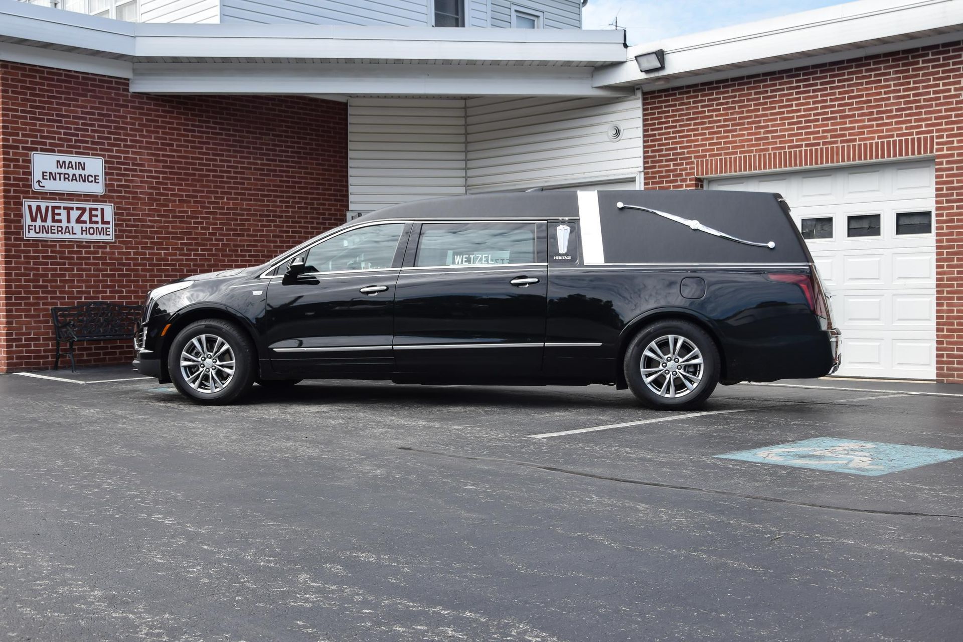 Black hearse parked beside a brick building and garage door