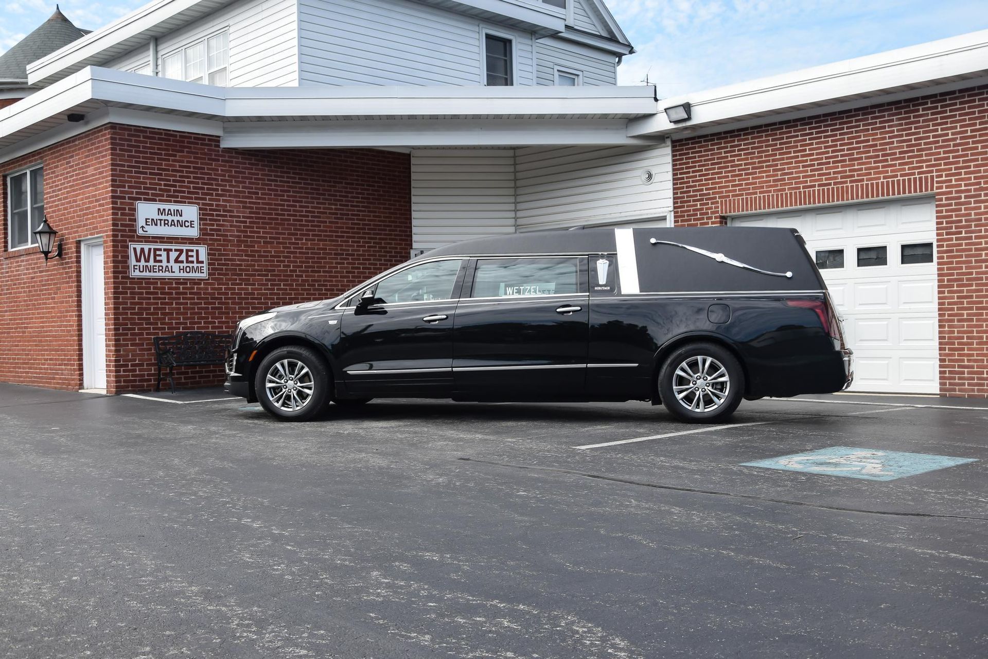 Black minivan parked outside a red-brick building with a white garage door.