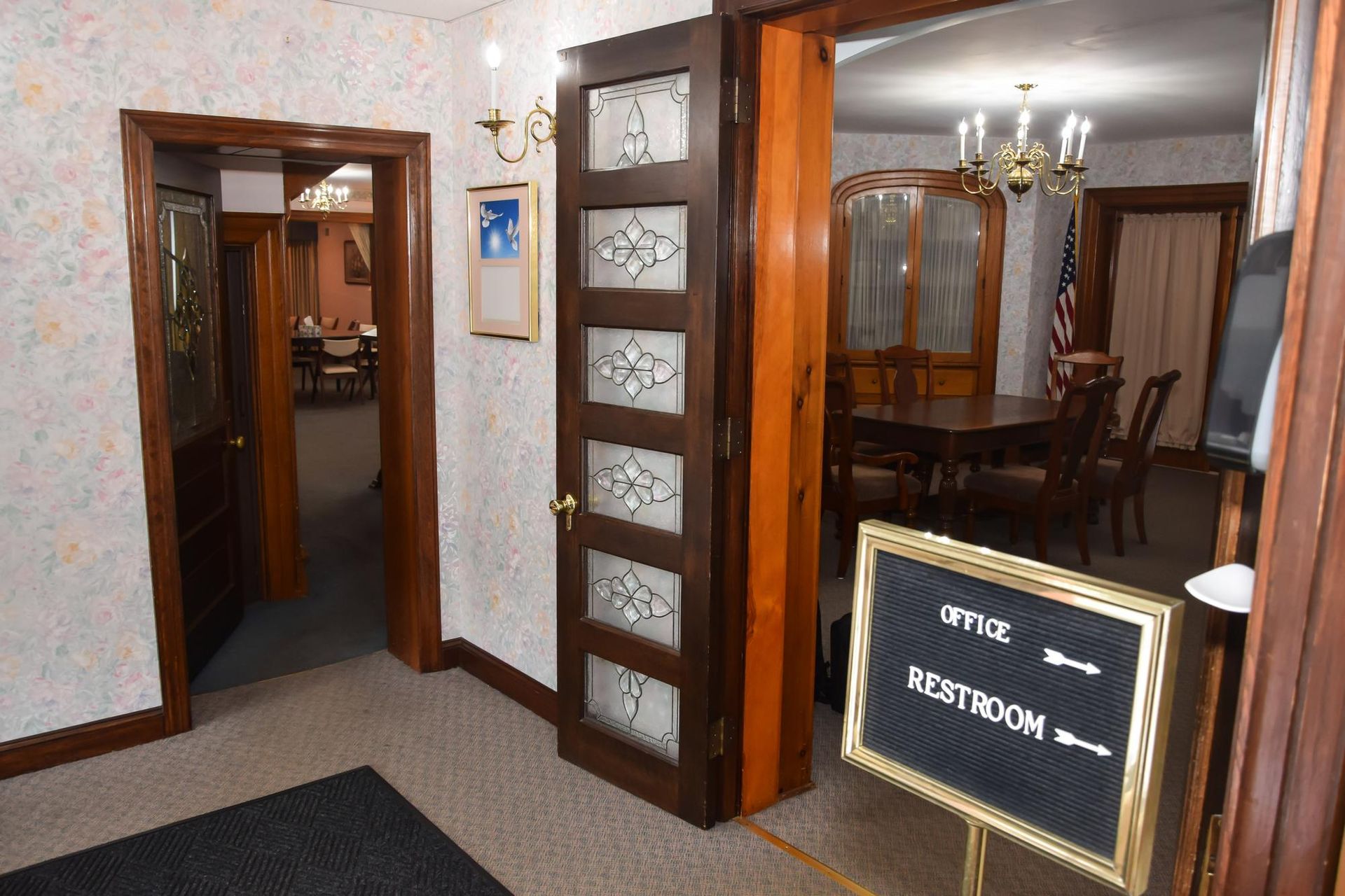 Wood-paneled lobby hallway with a sign reading “VESTIBULE” and adjoining rooms visible through open doors.