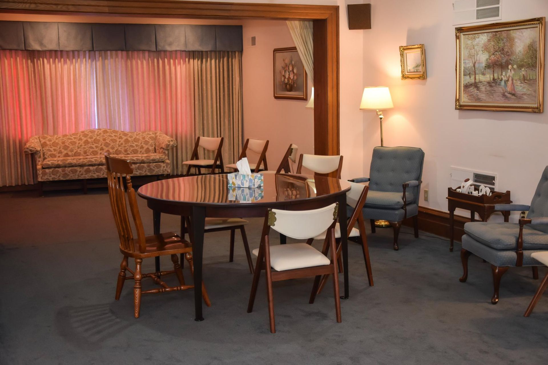 Cozy living room with round dining table, chairs, sofa alcove, lamp, and framed wall art