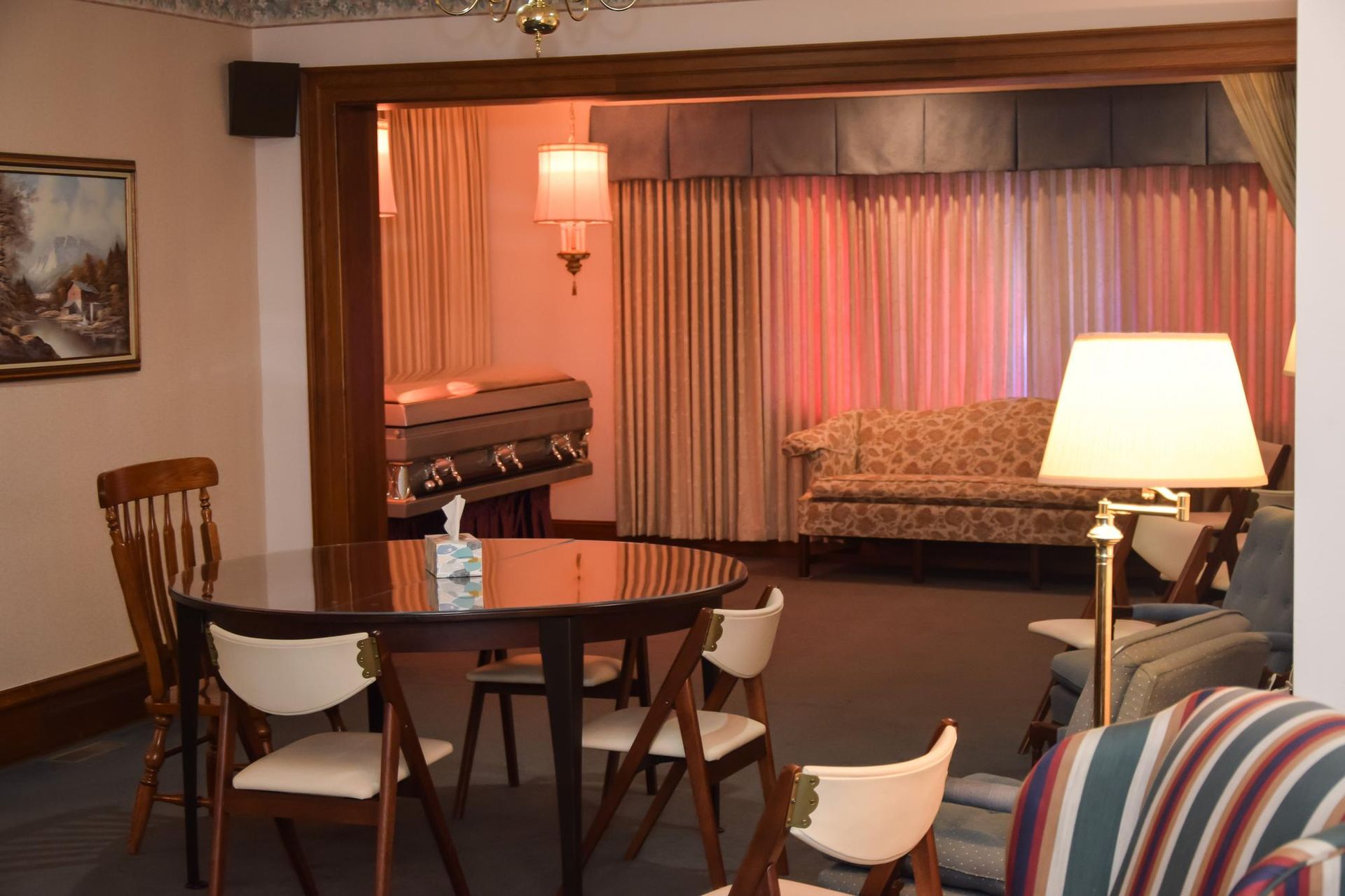 Cozy living room with round table, chairs, sofa, lamp, and curtained window alcove