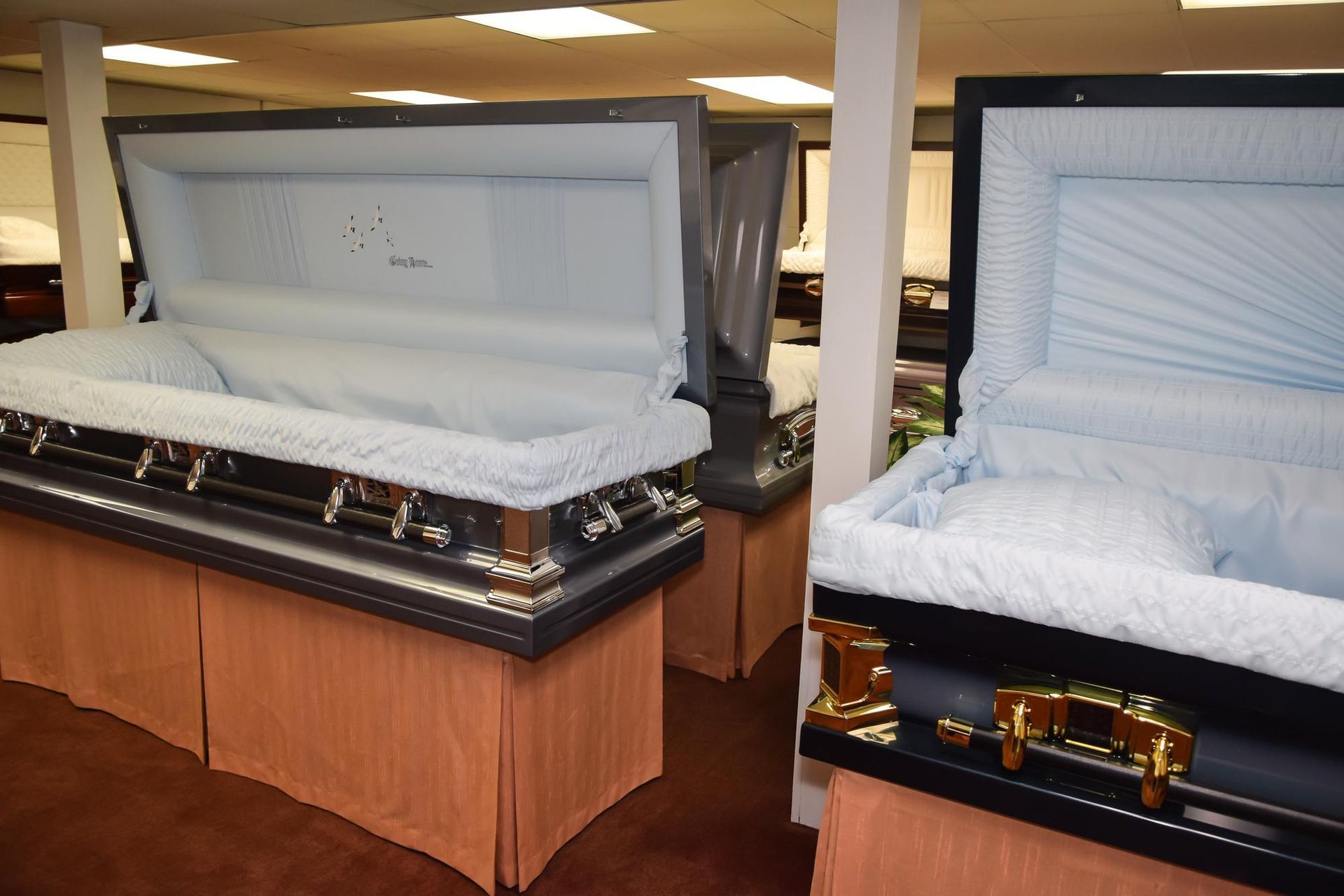 Two open caskets on display in a funeral home showroom