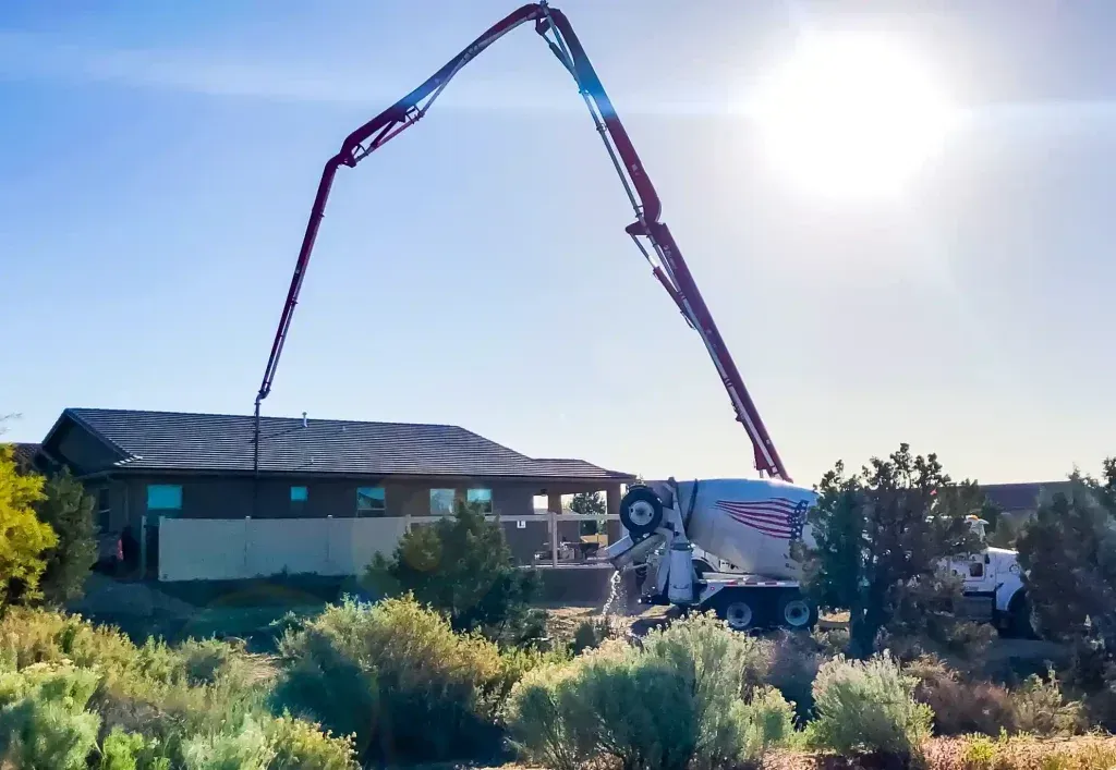 A concrete pump is pouring concrete in front of a house.