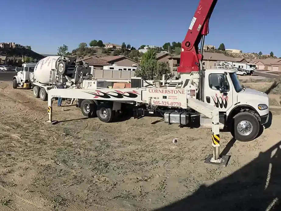 A concrete pump truck is parked in a dirt field.