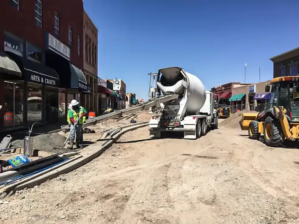 A concrete mixer truck is driving down a city street