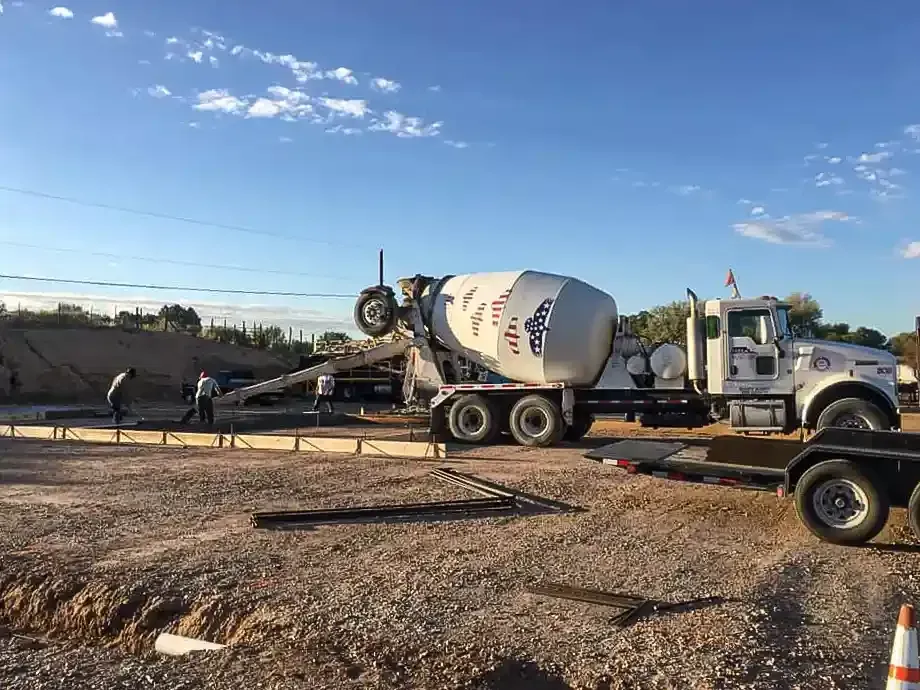 A concrete mixer truck is driving down a dirt road.