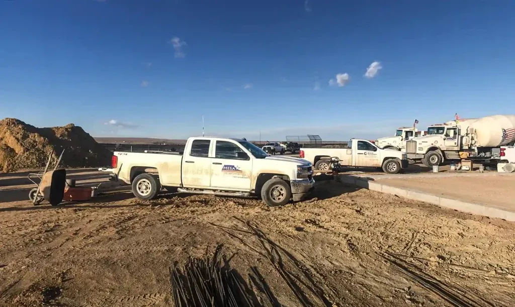 A white truck is parked in the dirt on a construction site.