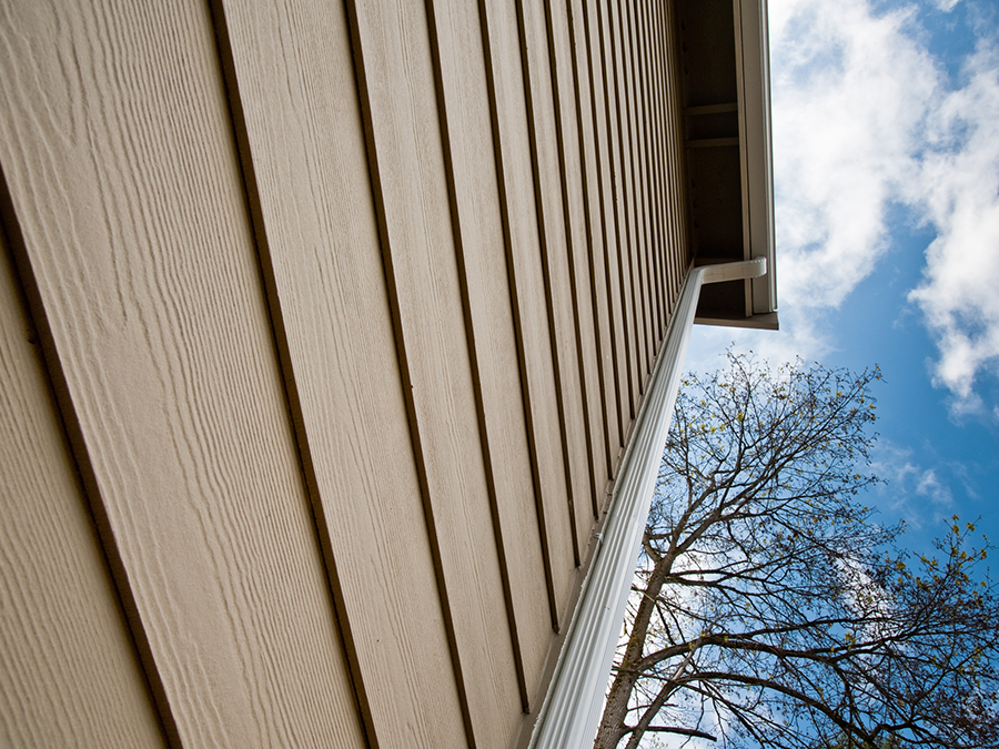 Looking up at the side of a house with a tree in the background.