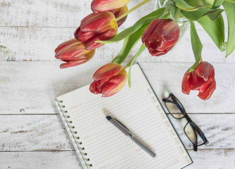 Vase of red tulips beside lined notebook and glasses, Hudson Oaks, TX pre-plan funerals