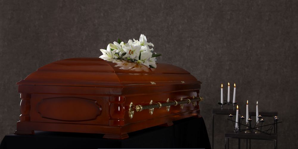 Wooden casket with white flowers and memorial candles symbolizing services from a funeral home and cremations provider in Annetta, TX