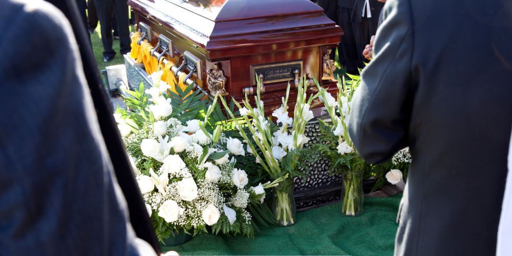 Graveside funeral service with a wooden casket surrounded by white flowers at a funeral home and cremations in Aledo, TX
