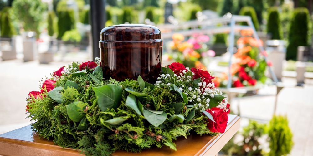 Cremation urn with red roses and greenery at a memorial ceremony by a funeral home and cremations in Hudson Oaks, TX