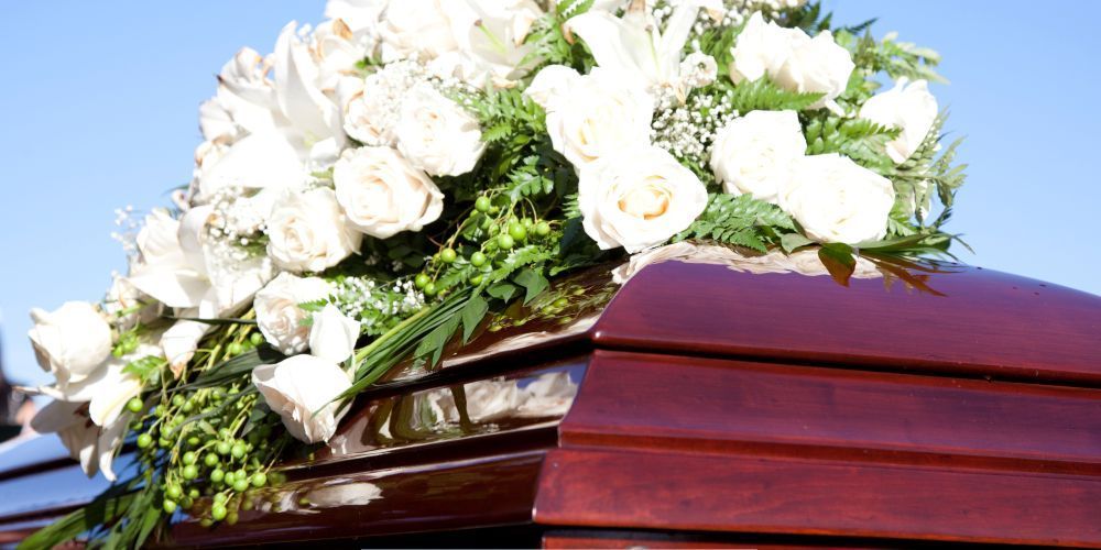 White rose funeral arrangement on casket during burial service by a funeral home and cremations in Willow Park, TX