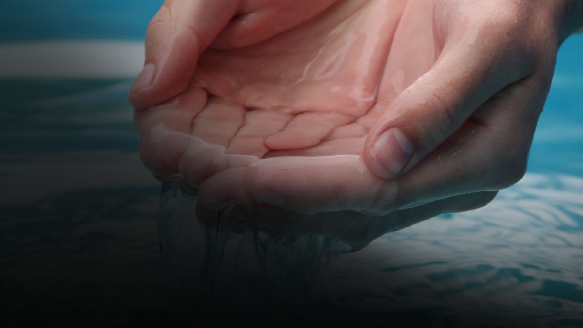 Hands cupped, holding and letting water flow through them, set against blue water backdrop.