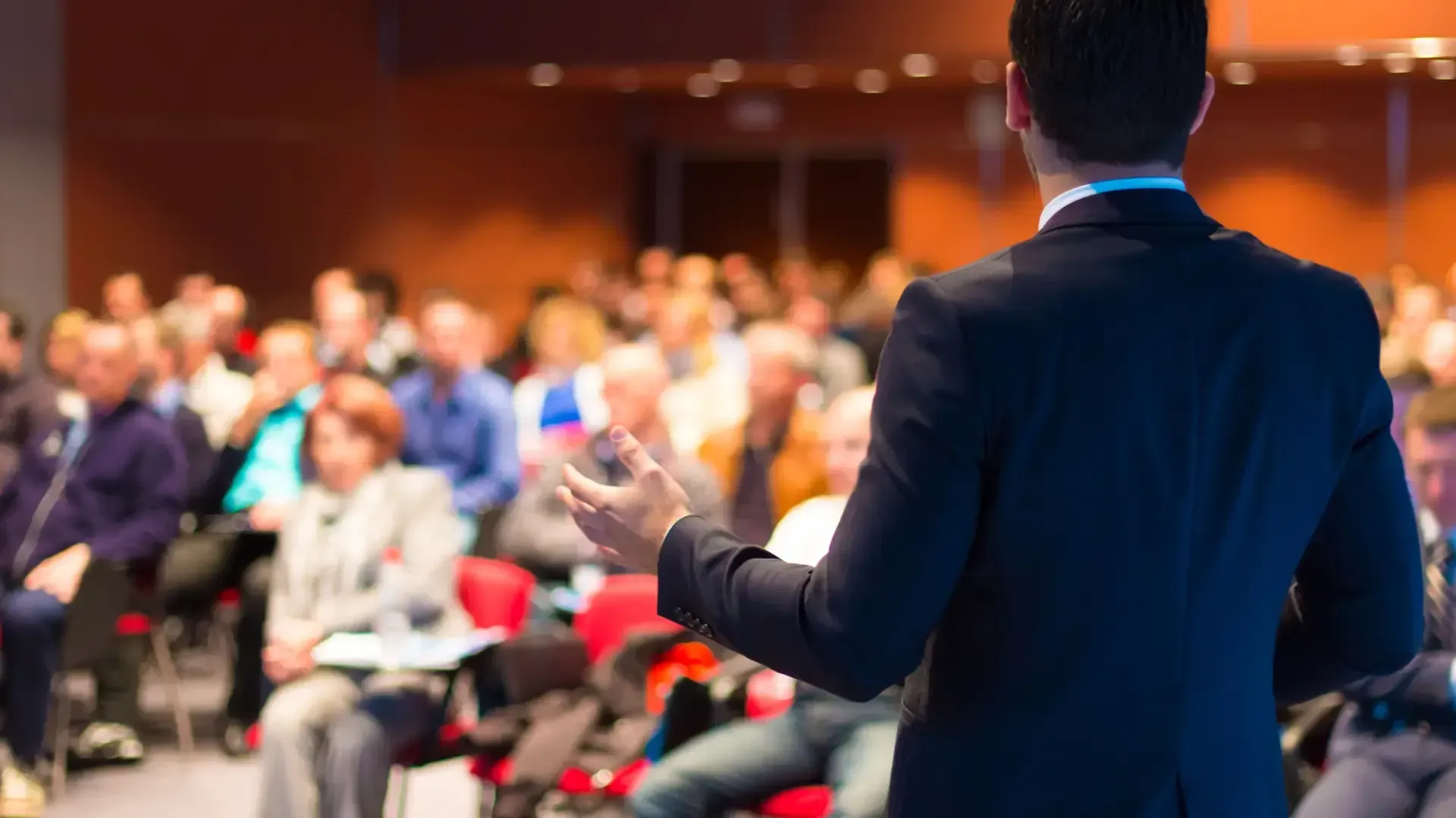 A man is giving a presentation to a crowd of people in a conference room.