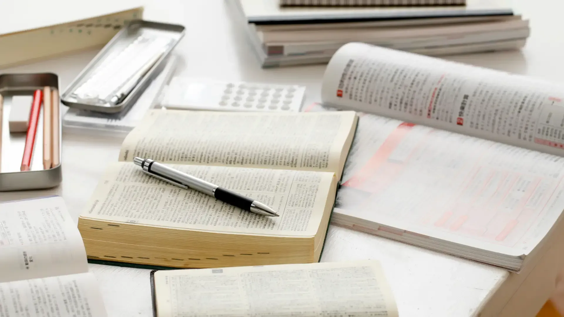 A pen is sitting on top of an open book on a desk.