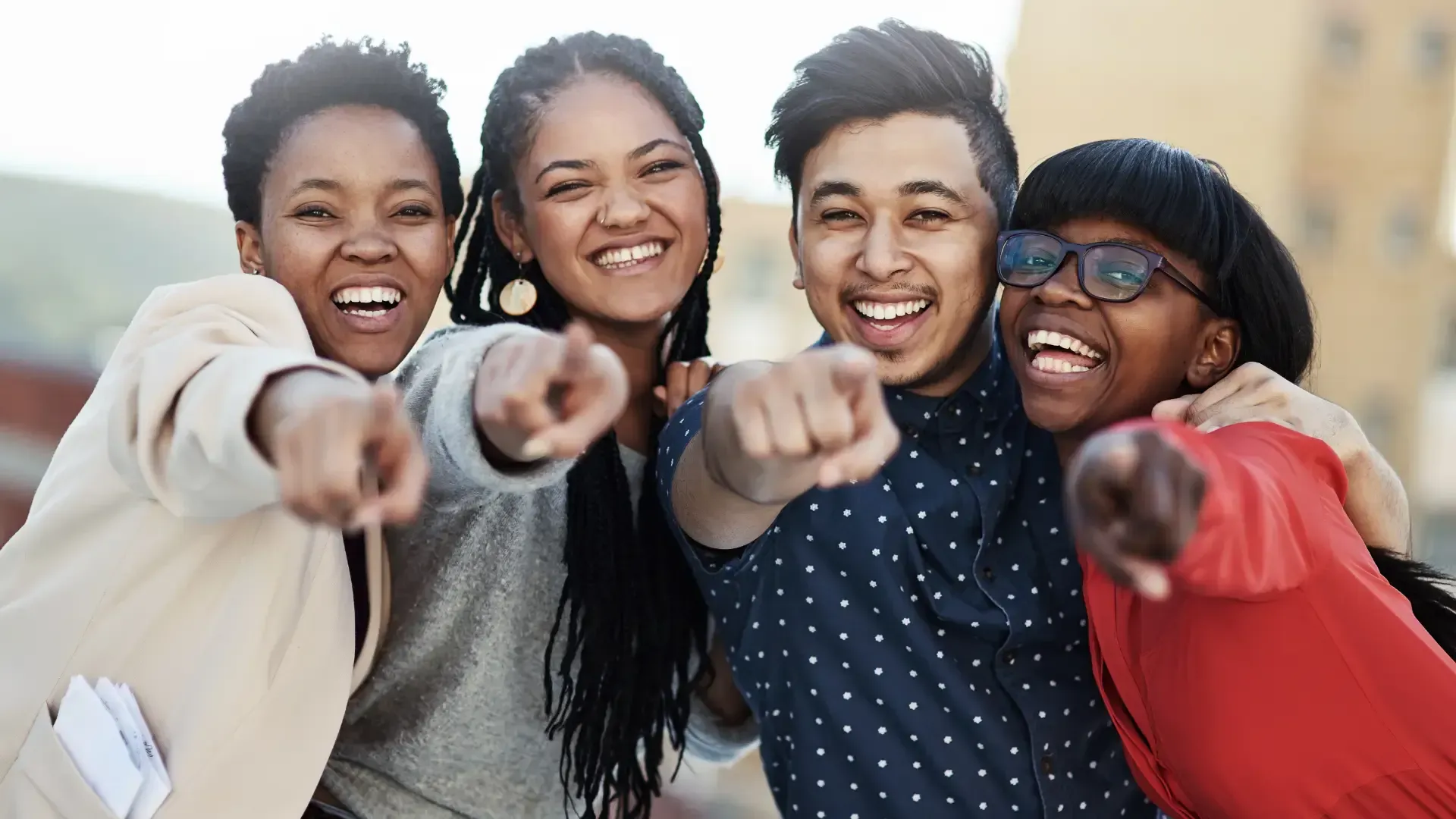 A group of young people are pointing at the camera.