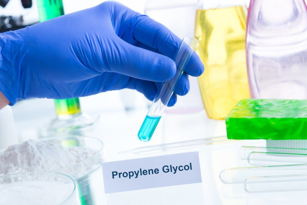 Gloved hand holding test tube with blue liquid, labeled