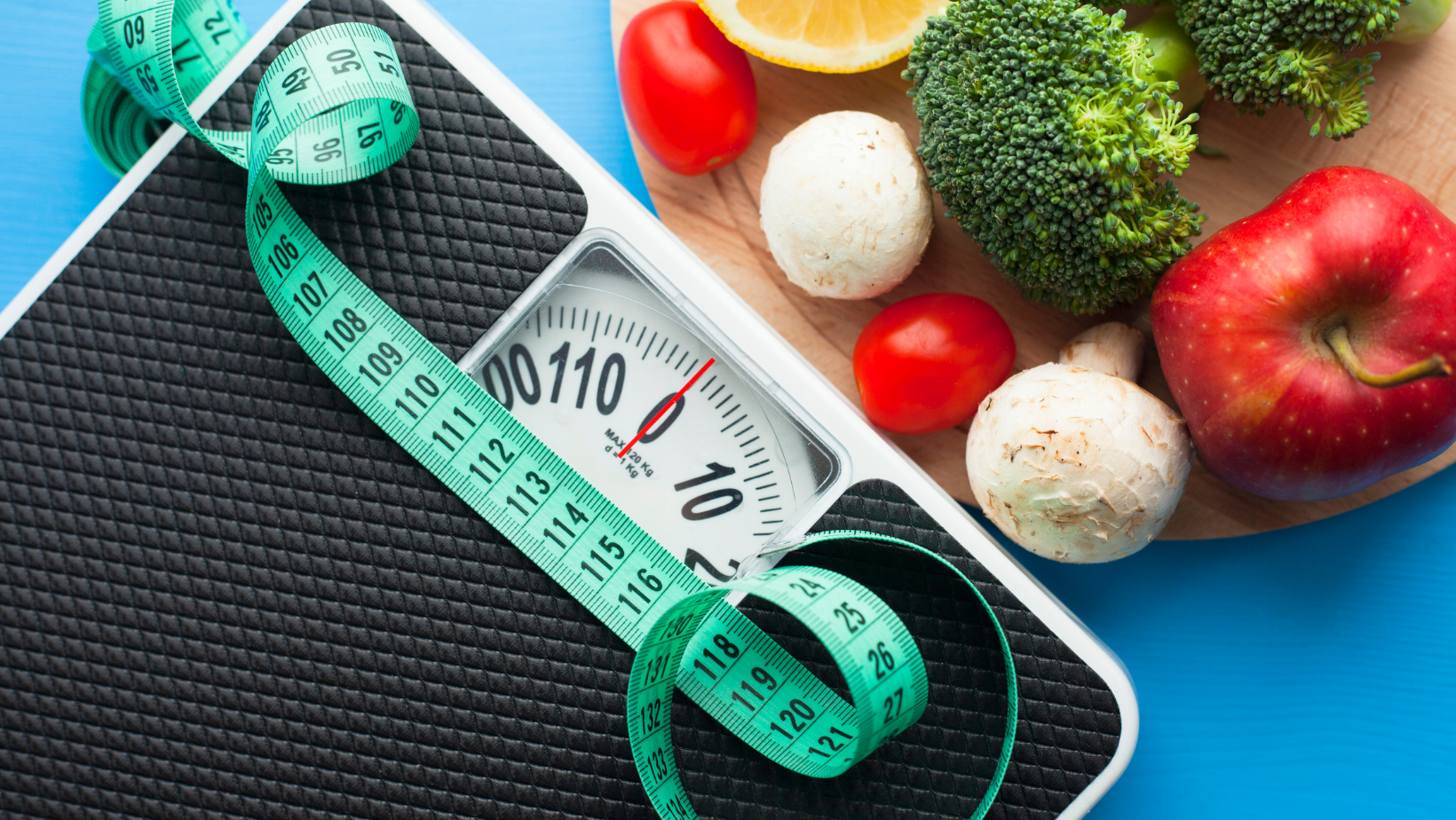 A scale with a measuring tape on it next to a plate of fruits and vegetables.