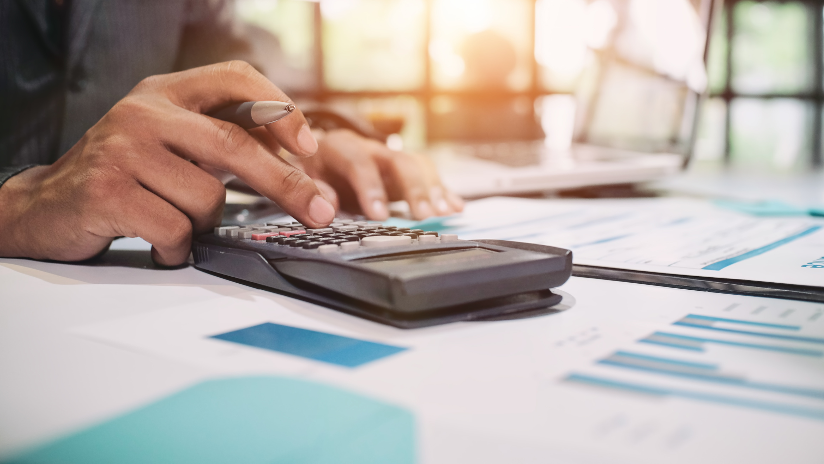 A man is using a calculator on a table.