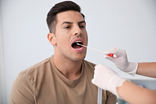 A man is getting a swab from his mouth.